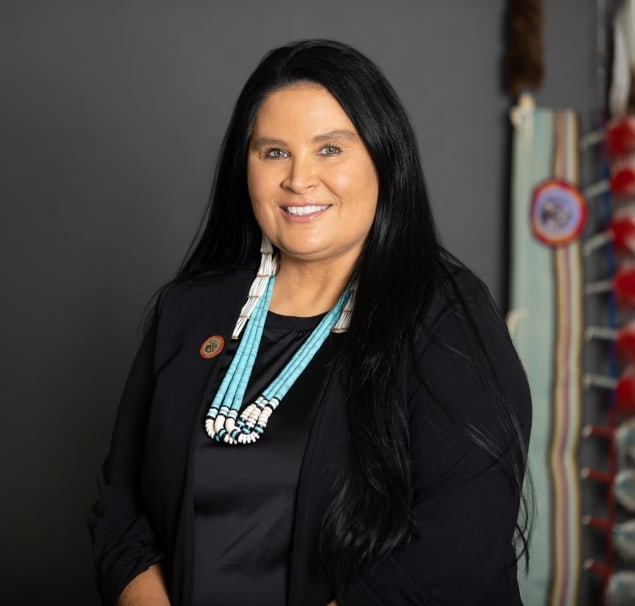 Headshot of woman in business attire and beaded jewelry