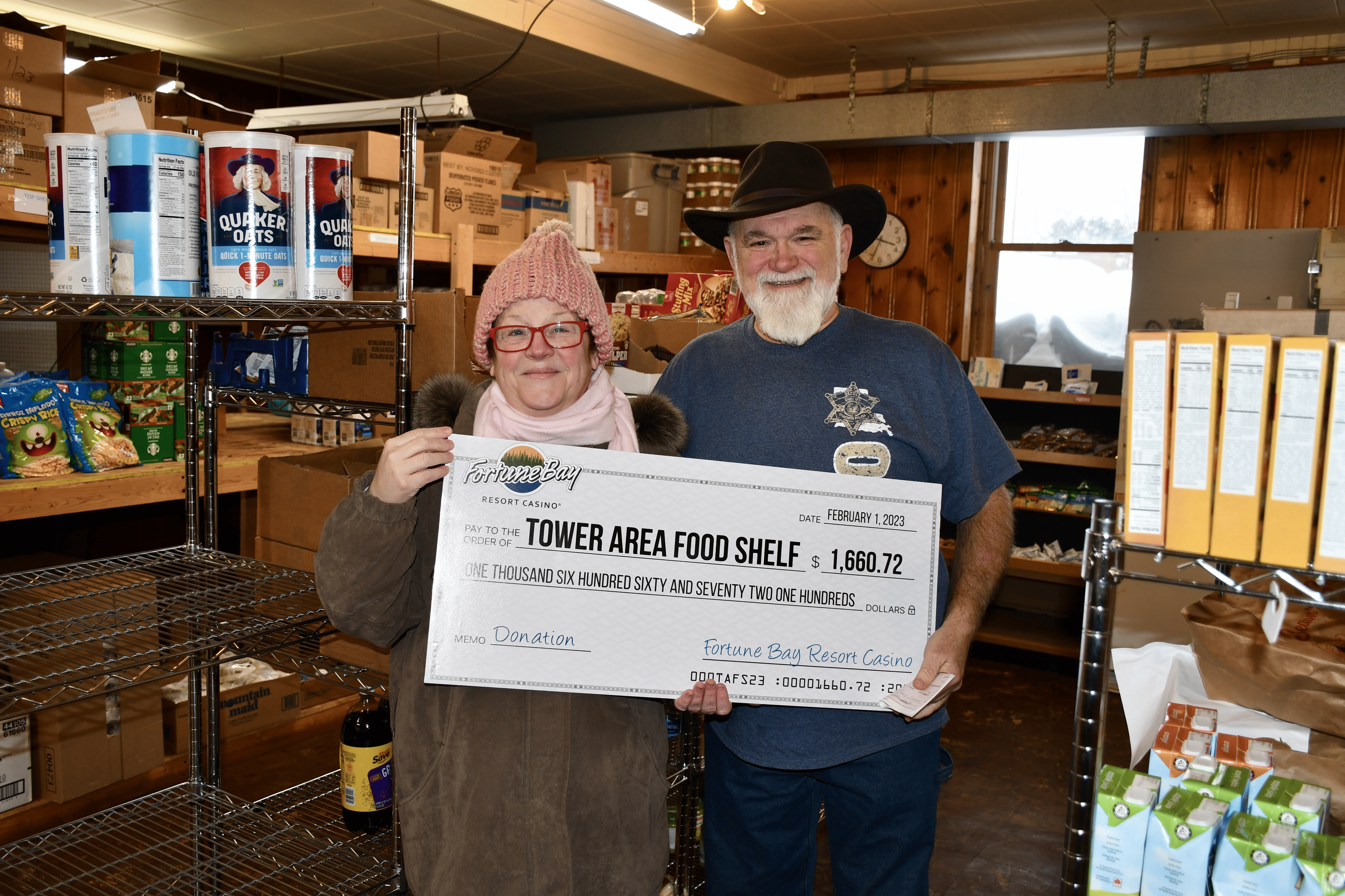 Two people holding a giant check at a food shelf.